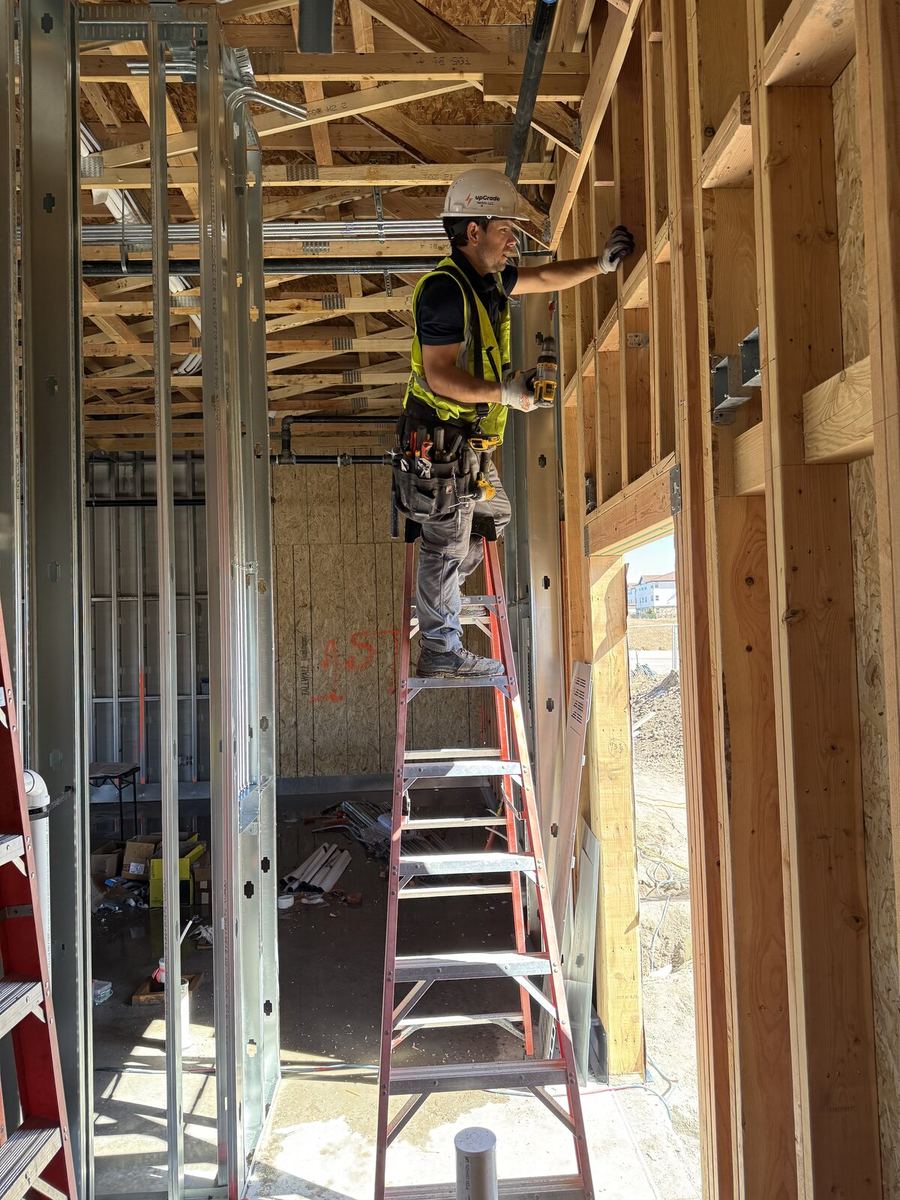 Licensed electrician on red ladder doing commercial rough-in
