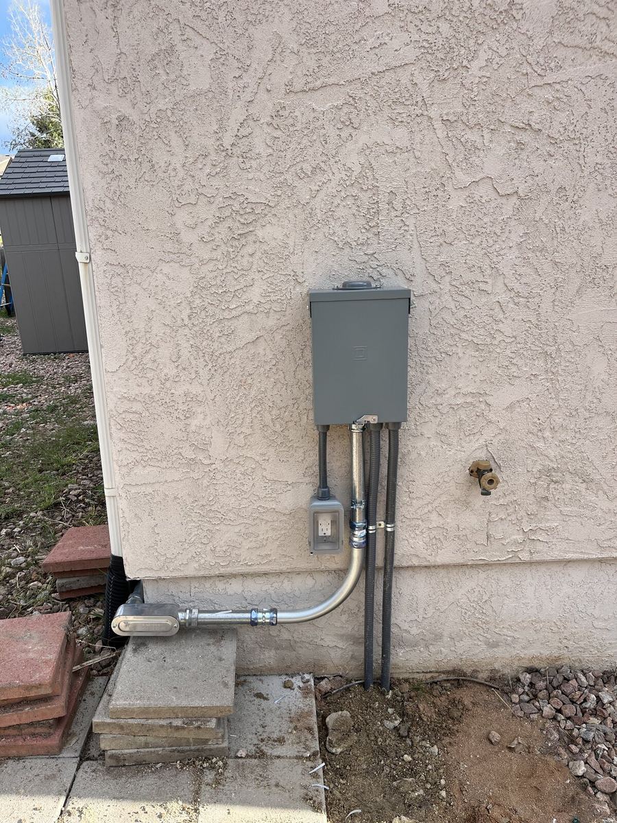 Exterior wall-mounted GFCI disconnect with conduit on stucco residence