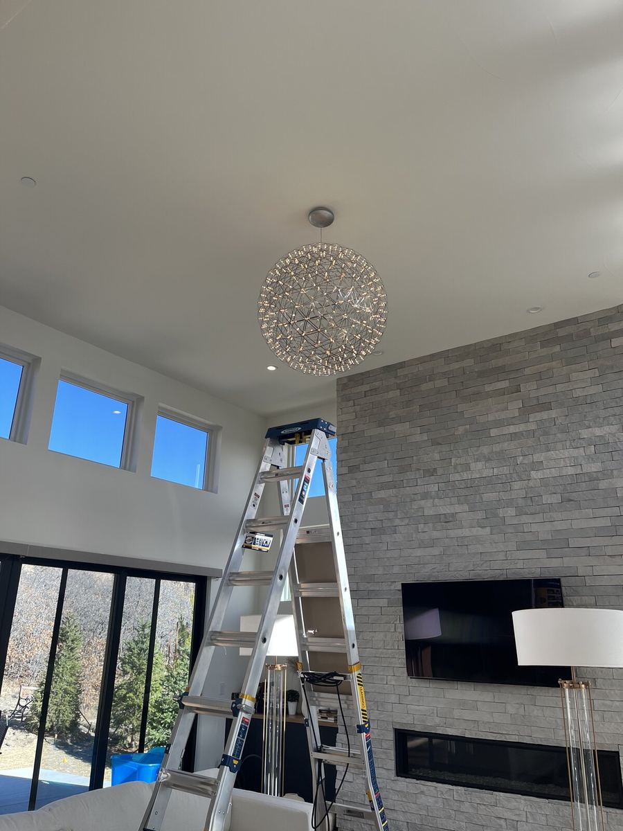 Modern sphere chandelier installation against stone fireplace wall