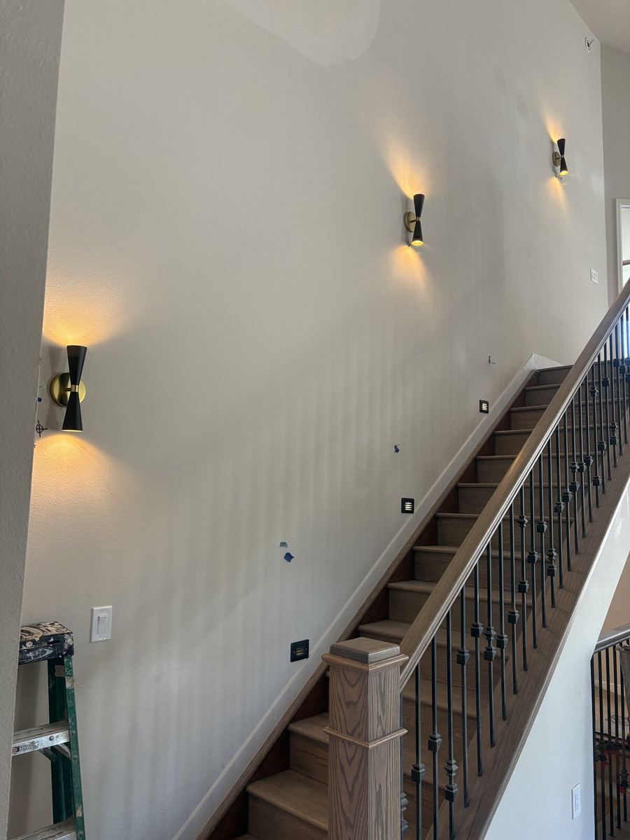 Modern black and brass wall sconces along stairway