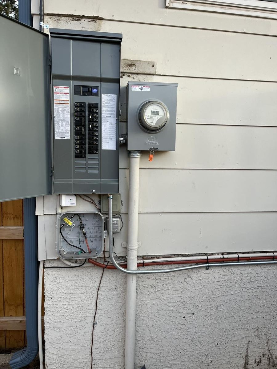 Completed 200A panel upgrade with new disconnect and meter on white siding